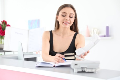 Photo of Young receptionist working at desk in beauty salon