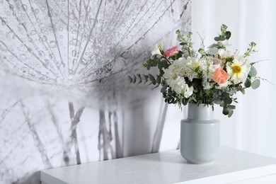 Photo of Bouquet with beautiful flowers on white chest of drawers indoors. Space for text