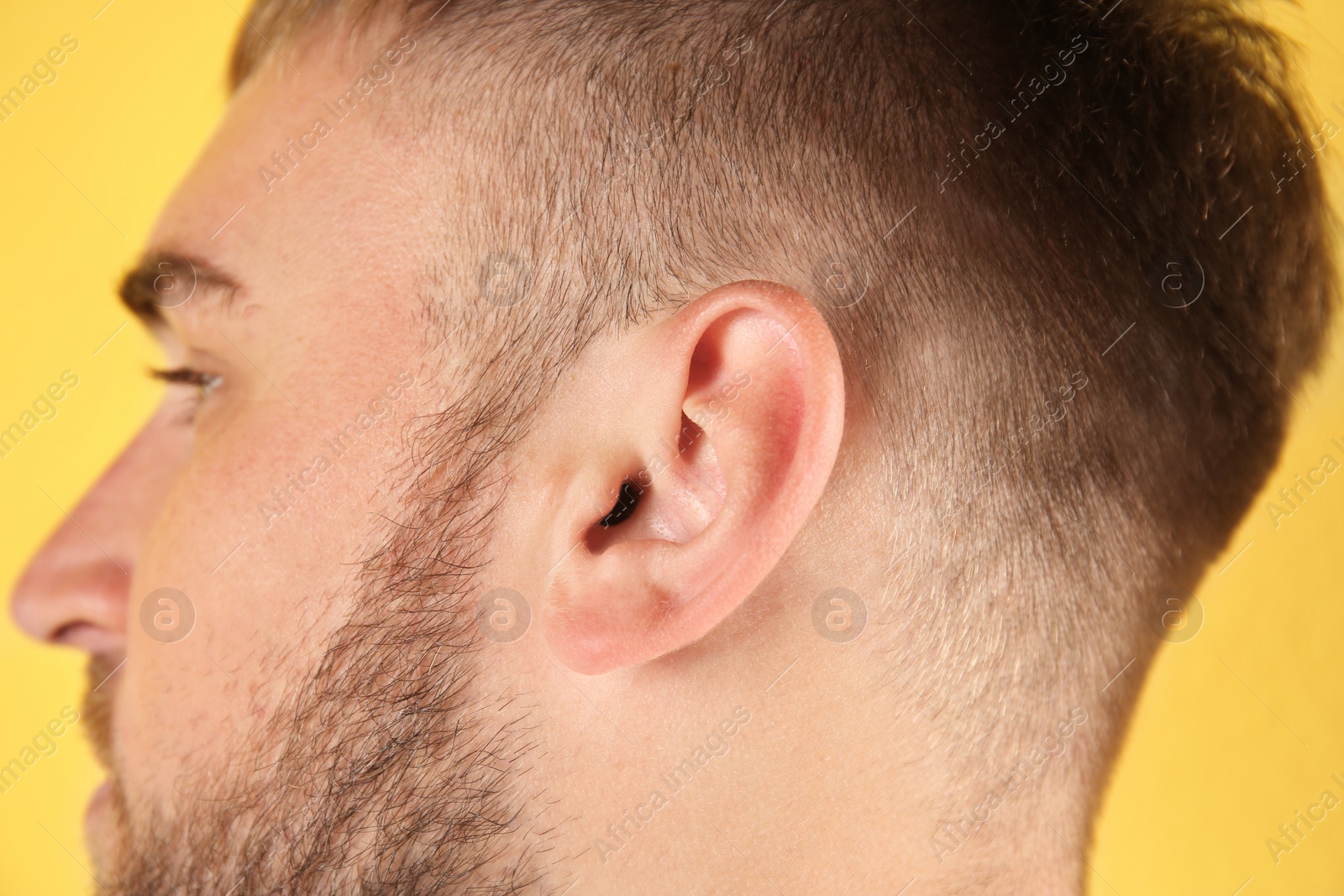 Photo of Young man on color background, closeup. Hearing problem