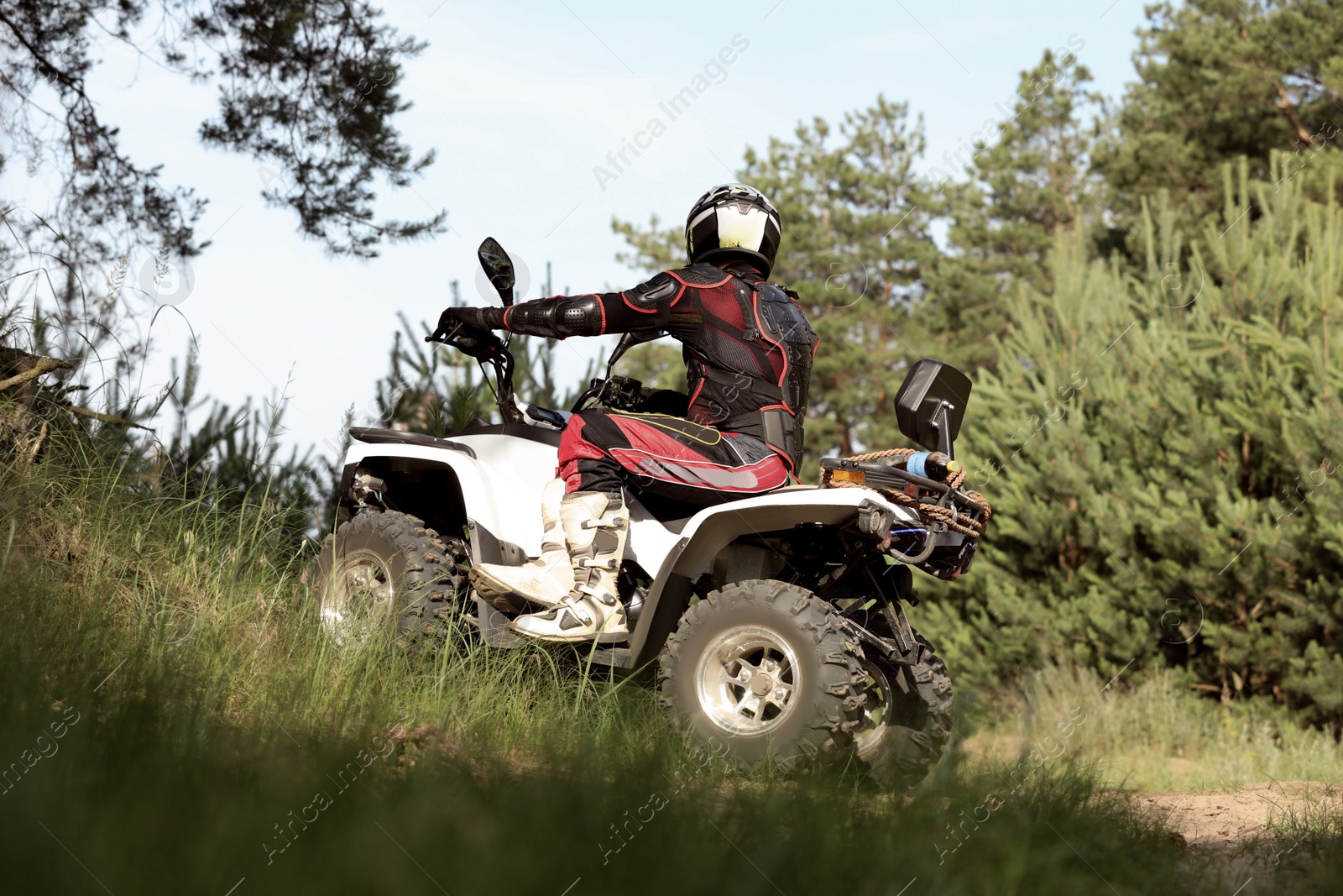 Photo of Man driving modern quad bike on sandy road near forest. Extreme sport