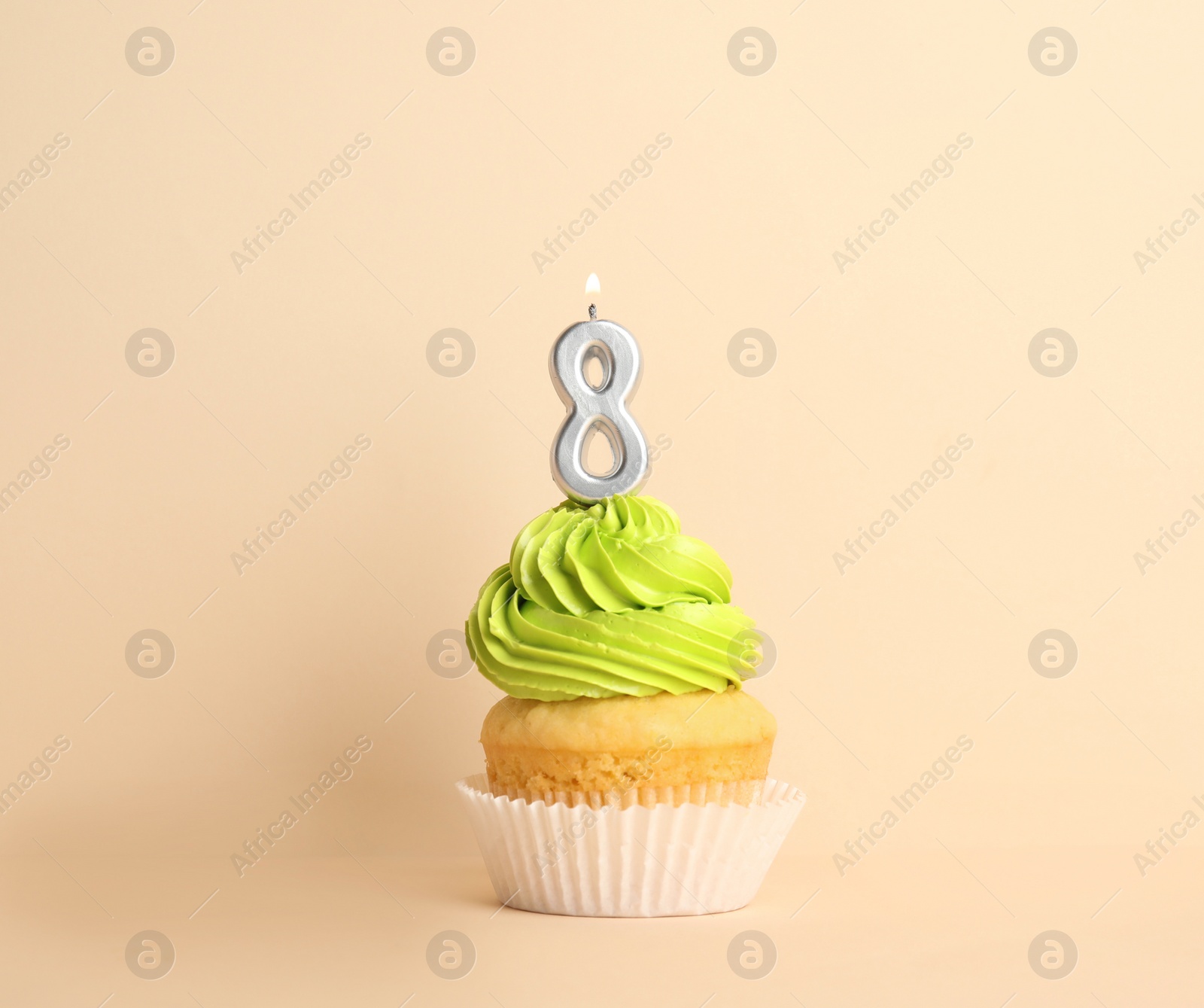 Photo of Birthday cupcake with number eight candle on beige background