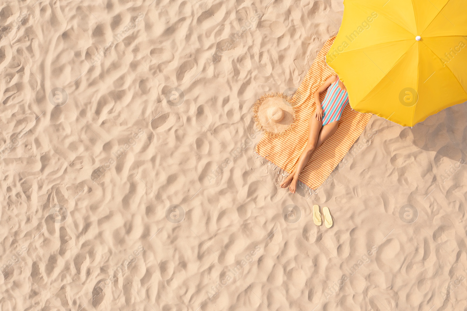 Image of Woman resting under yellow beach umbrella at sandy coast, aerial view. Space for text