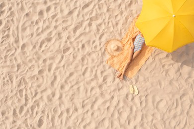 Image of Woman resting under yellow beach umbrella at sandy coast, aerial view. Space for text