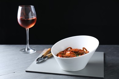 Photo of Delicious boiled crabs, glass of wine and cracker on grey table