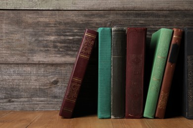 Photo of Different old hardcover books on wooden table, space for text