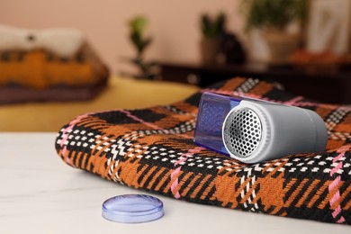 Photo of Modern fabric shaver and cloth on white table indoors, closeup. Space for text