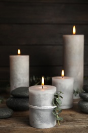 Photo of Composition with burning candles, spa stones and eucalyptus on wooden table, space for text