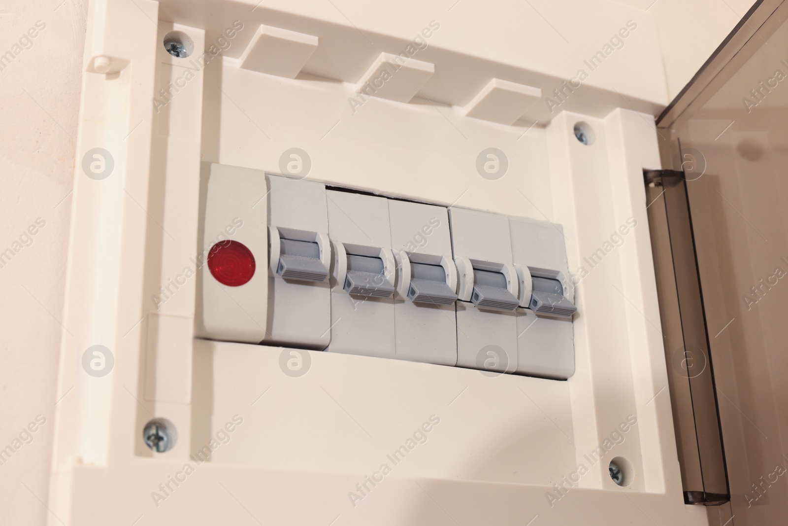 Photo of Open fuse box on beige wall, closeup