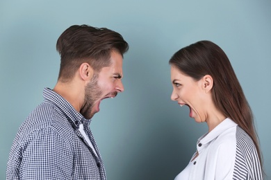 Young couple having argument on color background. Relationship problems