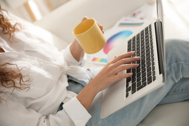 Professional designer working with laptop on sofa, closeup