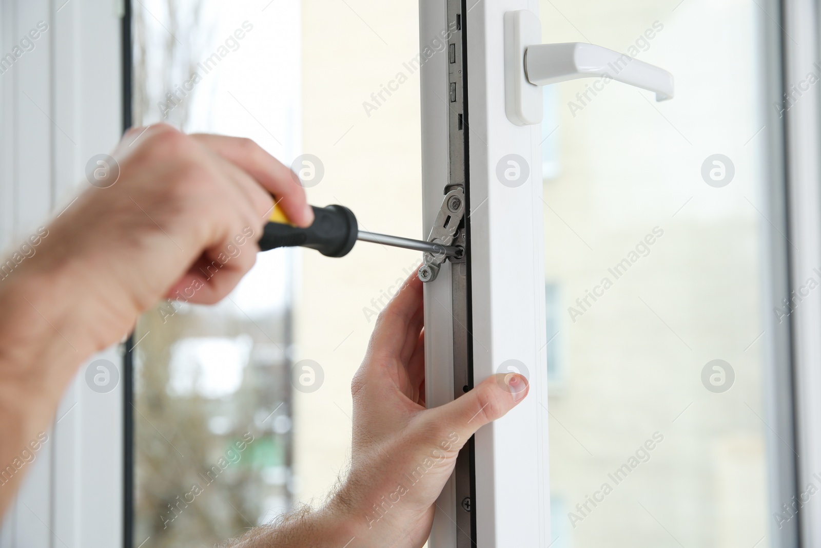 Photo of Construction worker adjusting installed window with screwdriver indoors, closeup