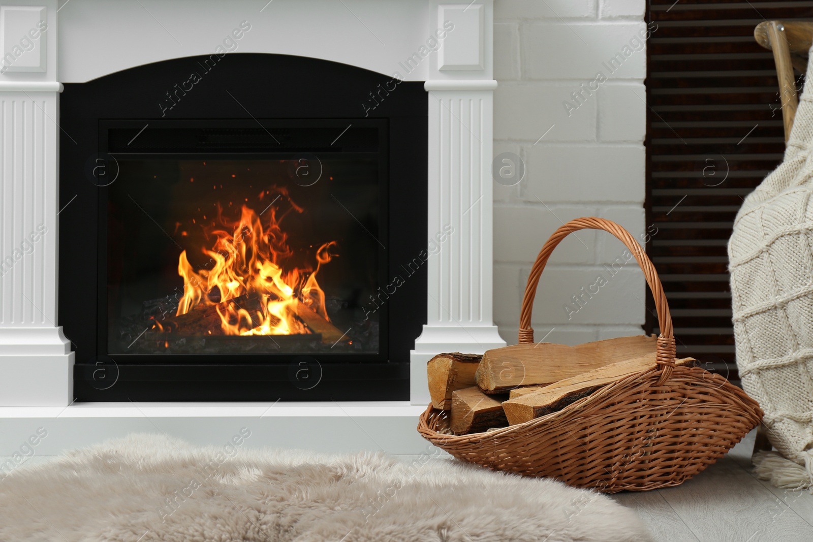 Photo of Firewood in wicker basket near fireplace indoors