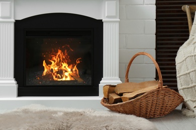 Firewood in wicker basket near fireplace indoors