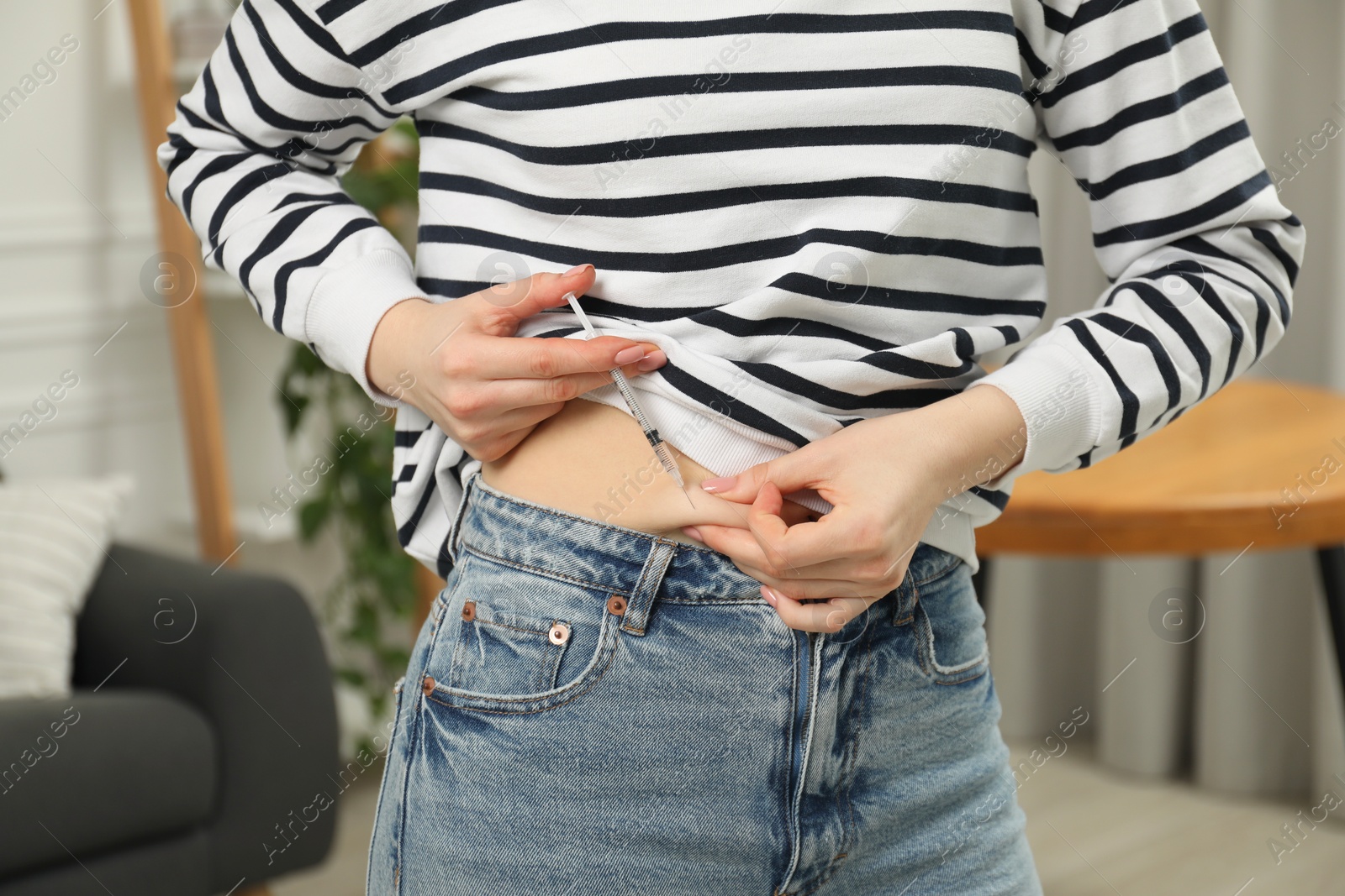 Photo of Diabetes. Woman making insulin injection into her belly indoors, closeup