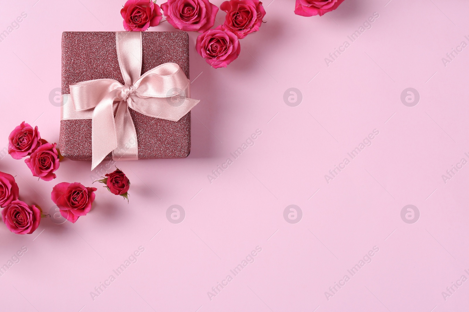 Photo of Beautiful roses and gift box on color background, top view. Space for text