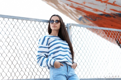 Young hipster woman in stylish jeans on pier