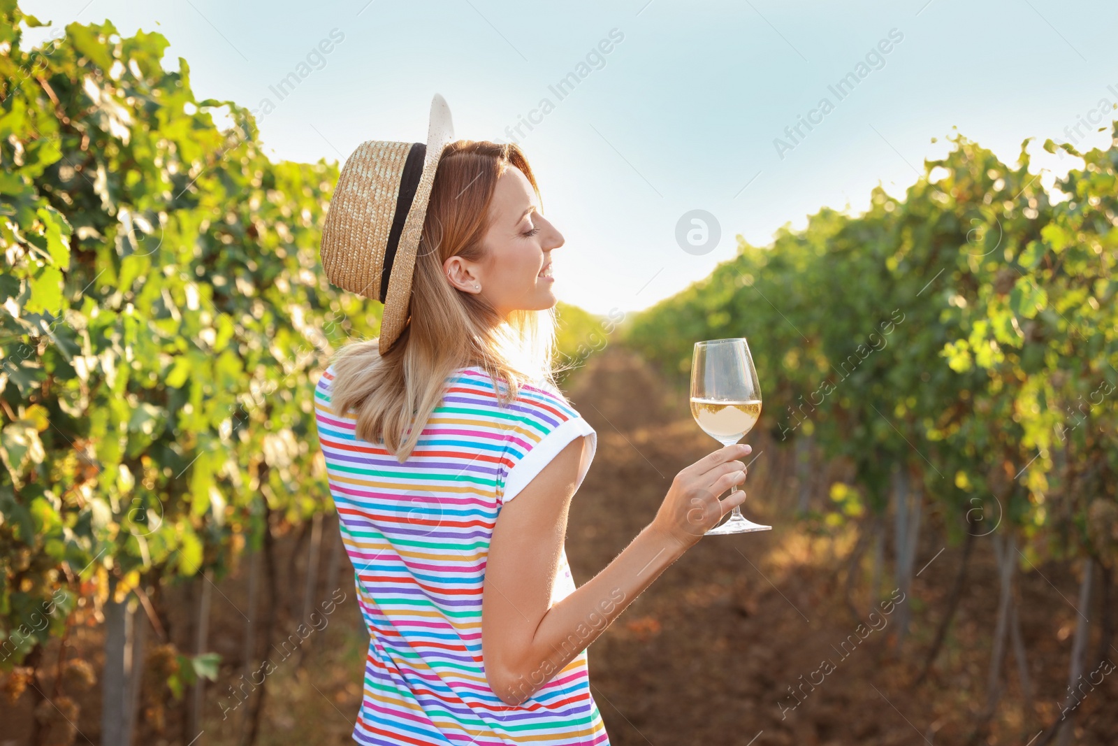 Photo of Young beautiful woman with glass of wine at vineyard on sunny day