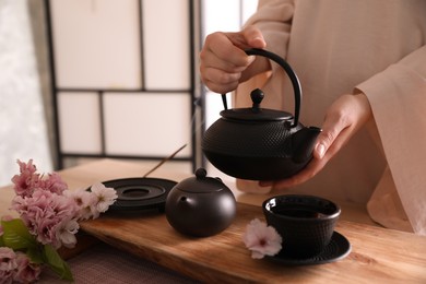 Photo of Master conducting traditional tea ceremony at table, closeup