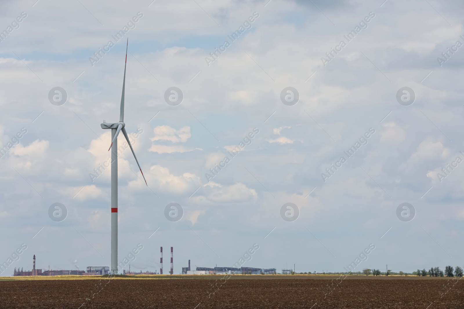 Photo of Modern wind turbine in field on cloudy day. Alternative energy source