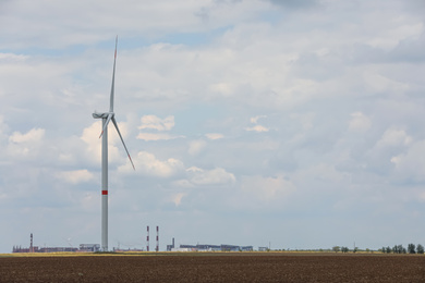 Photo of Modern wind turbine in field on cloudy day. Alternative energy source