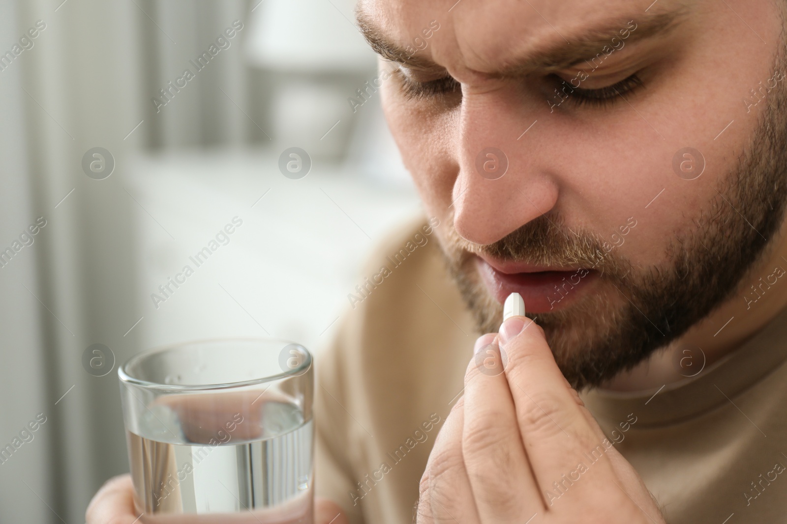 Photo of Man taking pill against migraine at home, closeup