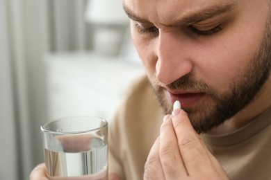 Photo of Man taking pill against migraine at home, closeup