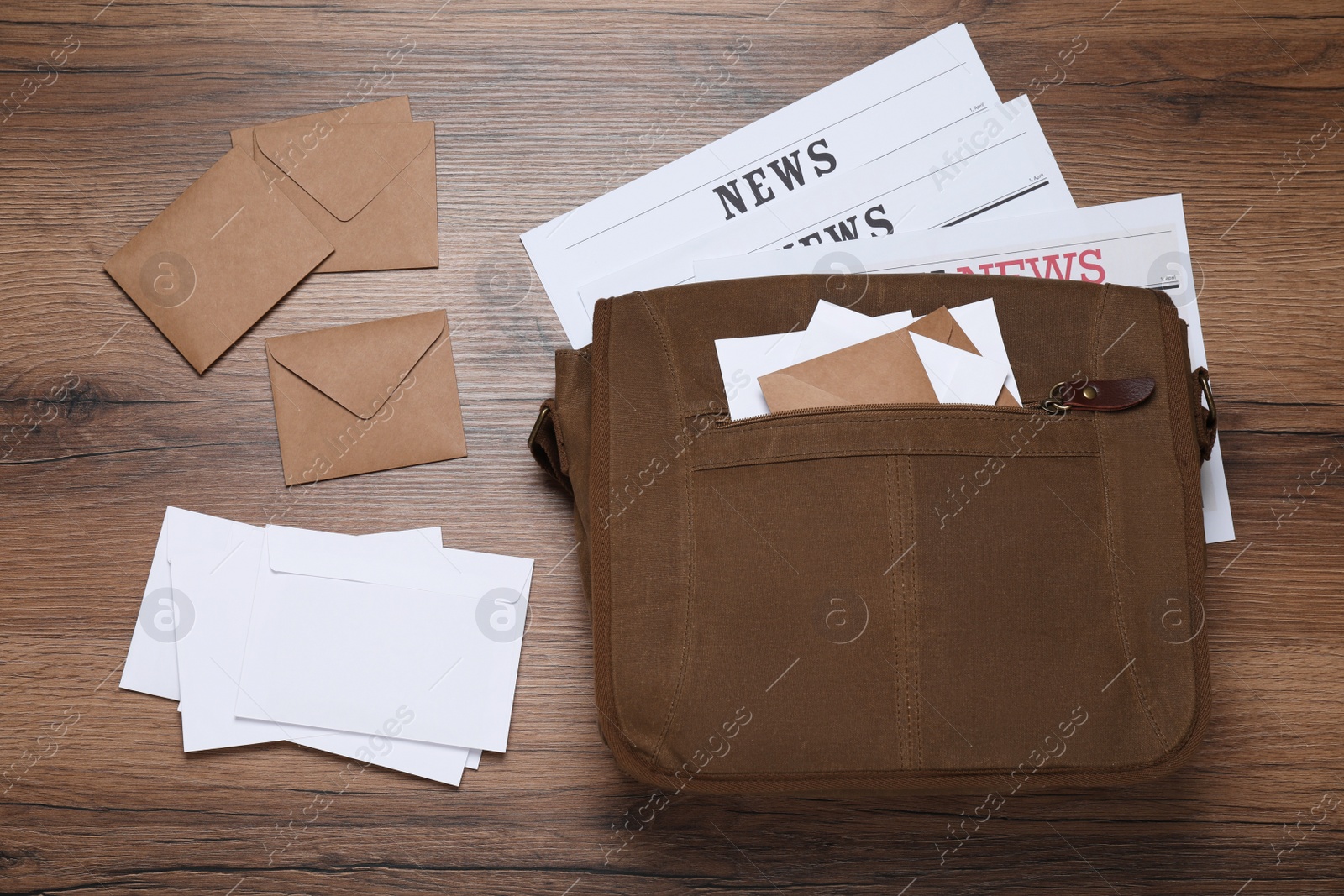 Photo of Postman bag, newspapers and mails on wooden table, flat lay