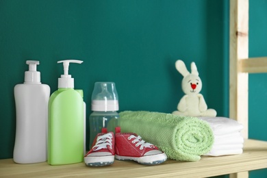 Photo of Bathroom accessories and toy for baby room interior on wooden shelf near turquoise wall