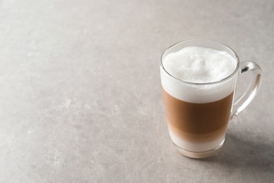 Photo of Hot coffee with milk in glass cup on light table. Space for text