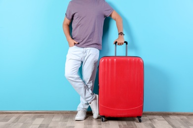 Photo of Man with suitcase near color wall. Vacation travel