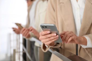 Young woman using modern smartphone indoors, closeup