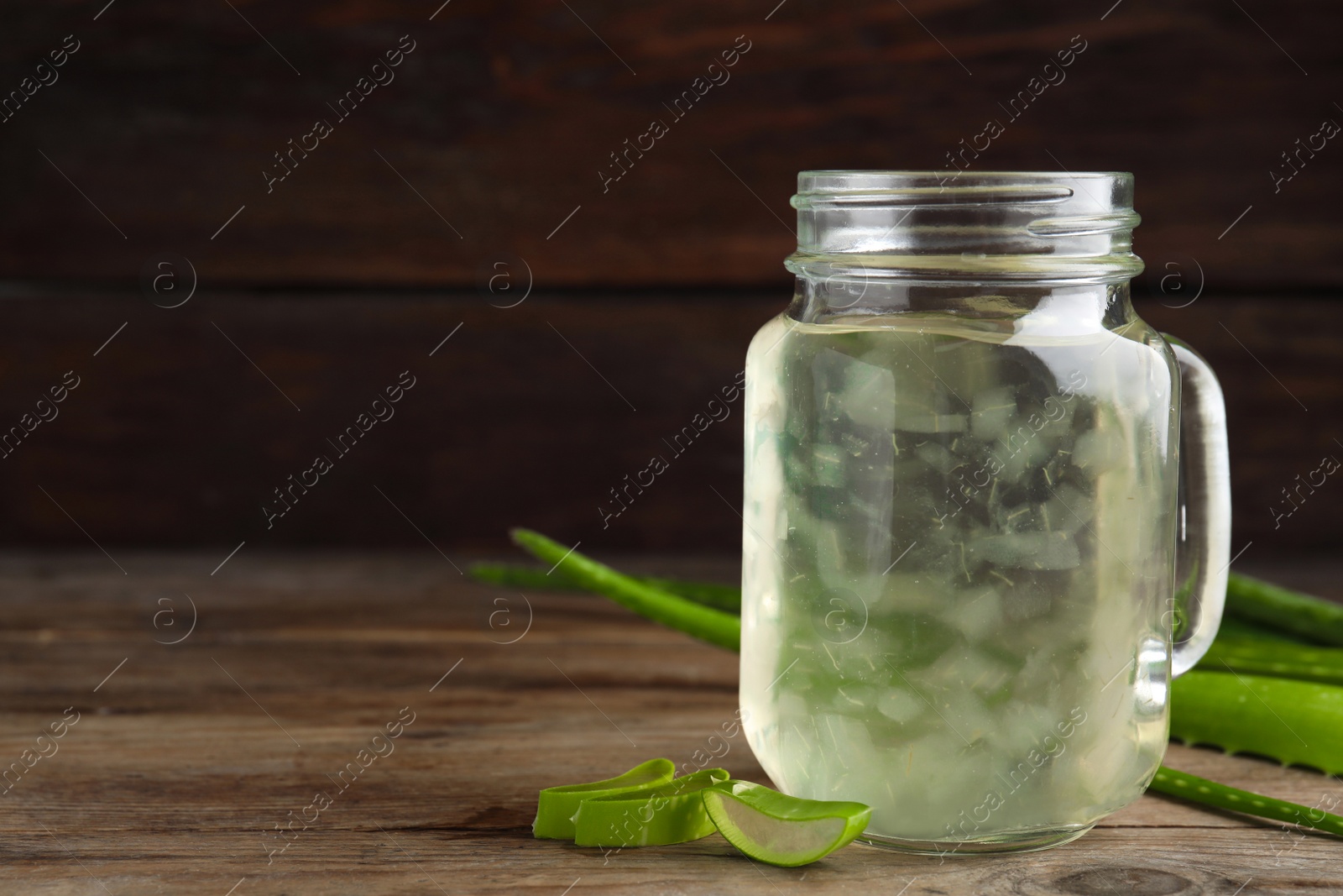 Photo of Fresh aloe drink in mason jar on wooden table. Space for text