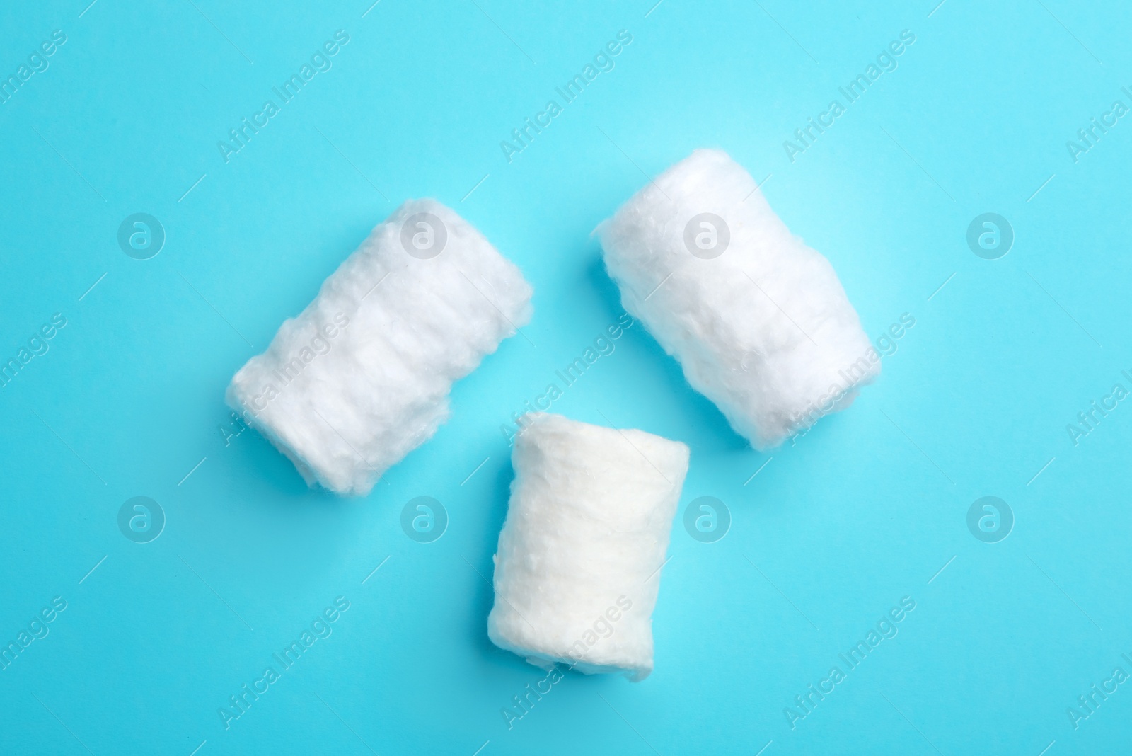 Photo of Three fluffy cotton rolls on color background, flat lay