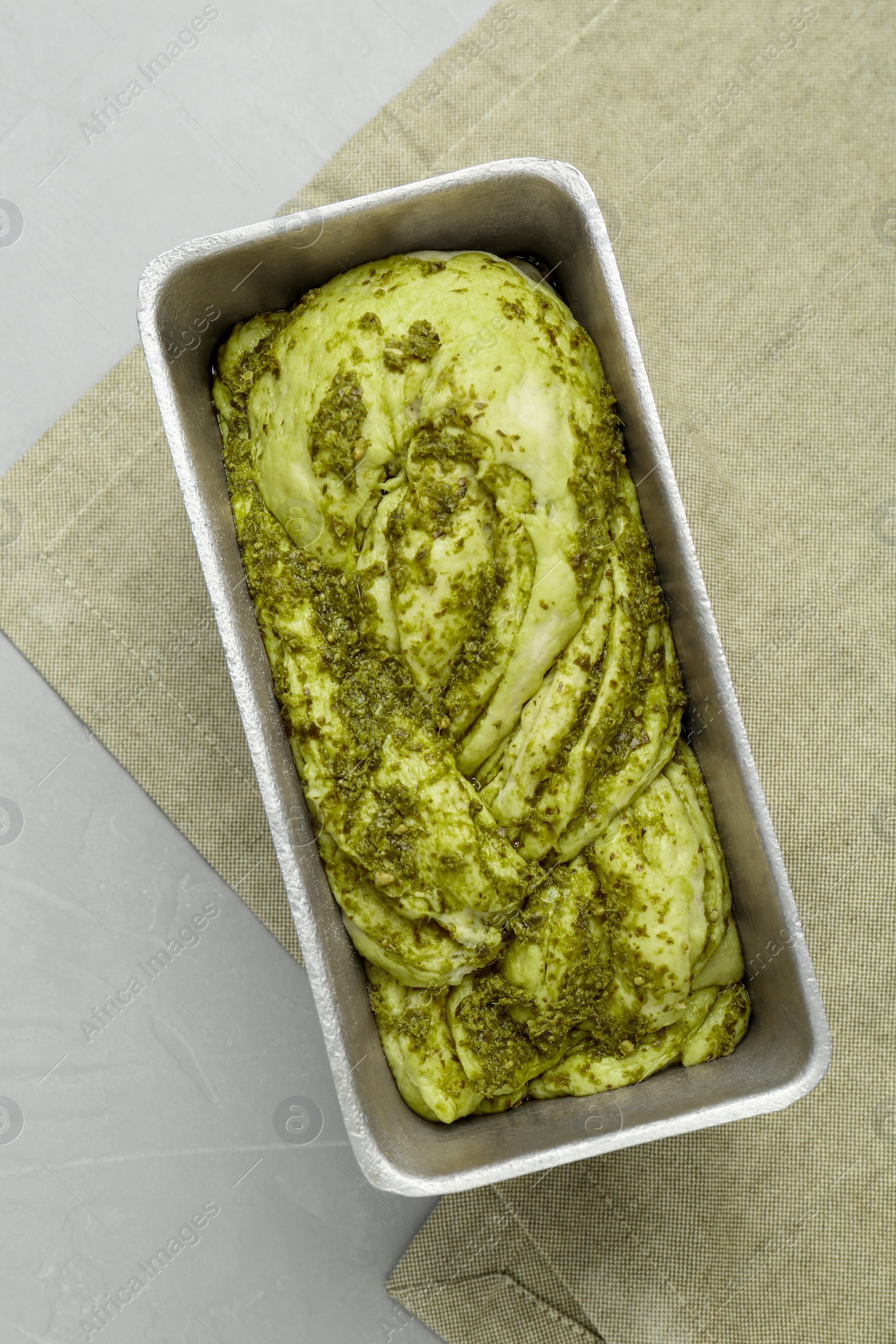 Photo of Uncooked pesto bread in baking dish on light table, top view