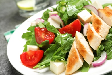 Delicious salad with meat, arugula and vegetables on grey table, closeup