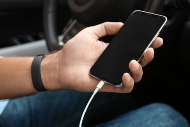 Photo of Man charging smartphone in car, closeup view