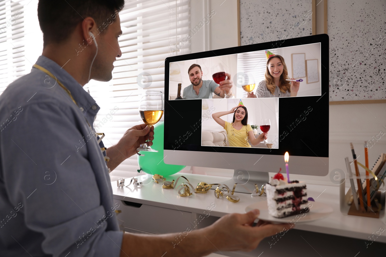 Image of Man with glass of wine and cake having online party via computer at home during quarantine lockdown