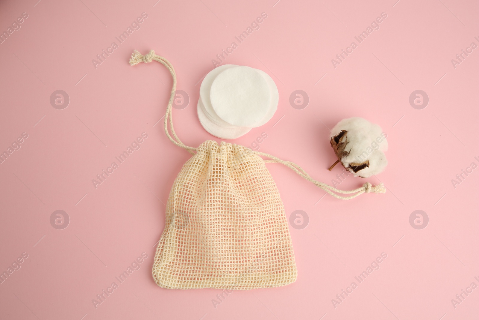 Photo of Bag, cotton pads and flower on pink background, flat lay