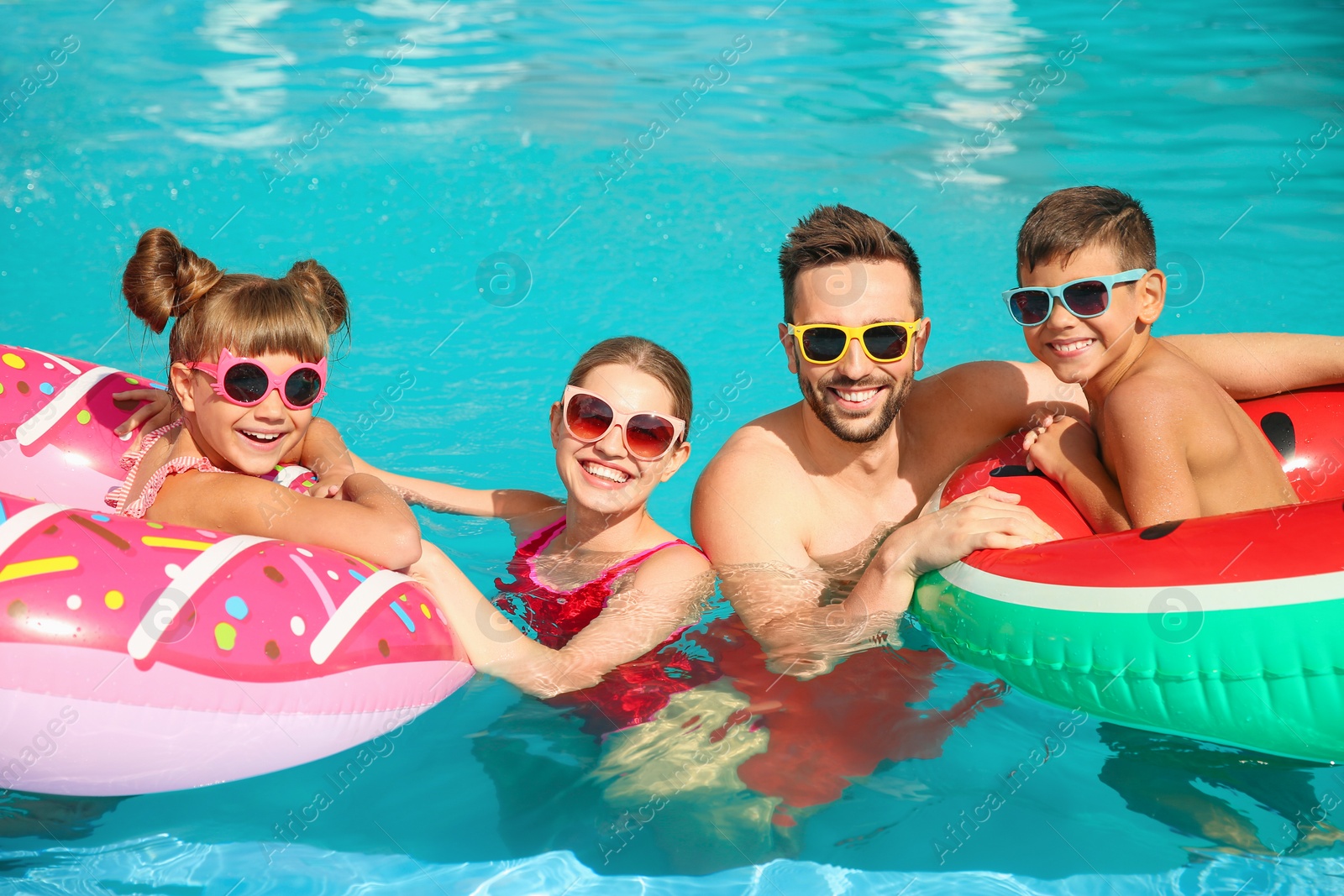 Photo of Happy family with inflatable rings in swimming pool