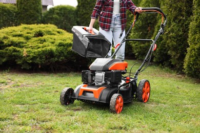 Photo of Woman with modern lawn mower in garden, closeup