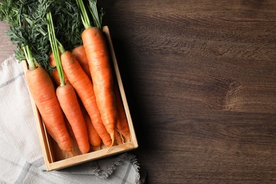 Tasty ripe carrots in crate on wooden table, top view. Space for text