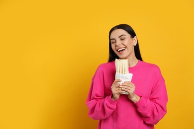 Young woman eating delicious shawarma on yellow background. Space for text