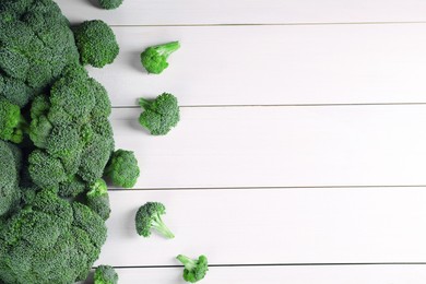 Photo of Fresh raw broccoli on white wooden table, flat lay. Space for text