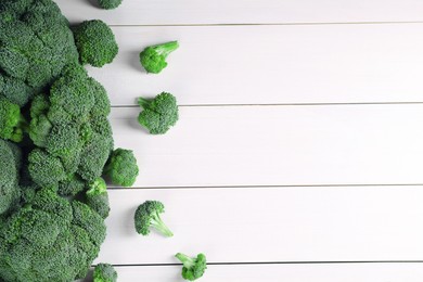 Fresh raw broccoli on white wooden table, flat lay. Space for text