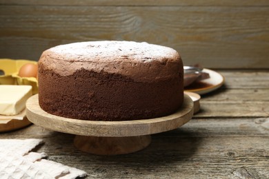 Photo of Tasty chocolate sponge cake with powdered sugar on wooden table