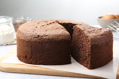 Photo of Cut chocolate sponge cake on light table, closeup