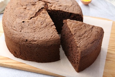 Photo of Cut chocolate sponge cake on table, closeup