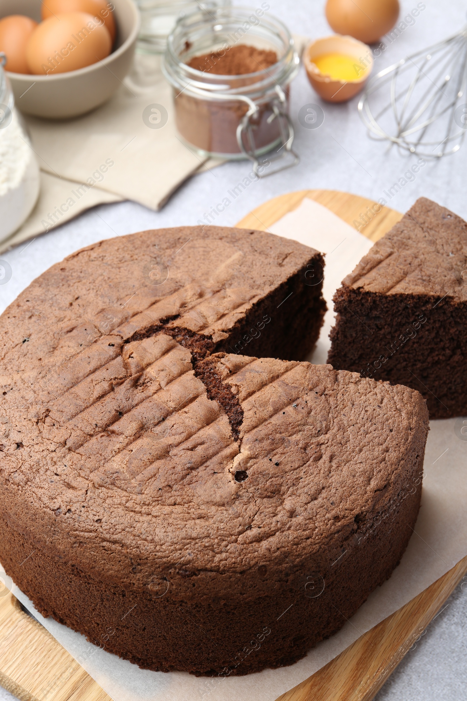 Photo of Cut chocolate sponge cake and ingredients on table, closeup