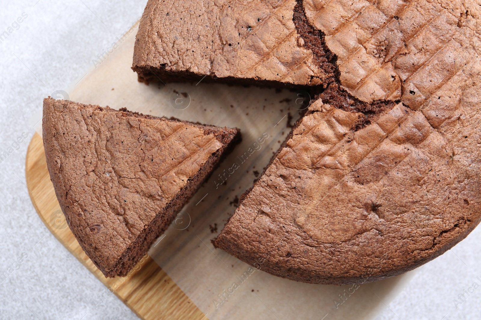 Photo of Cut chocolate sponge cake on light table, top view