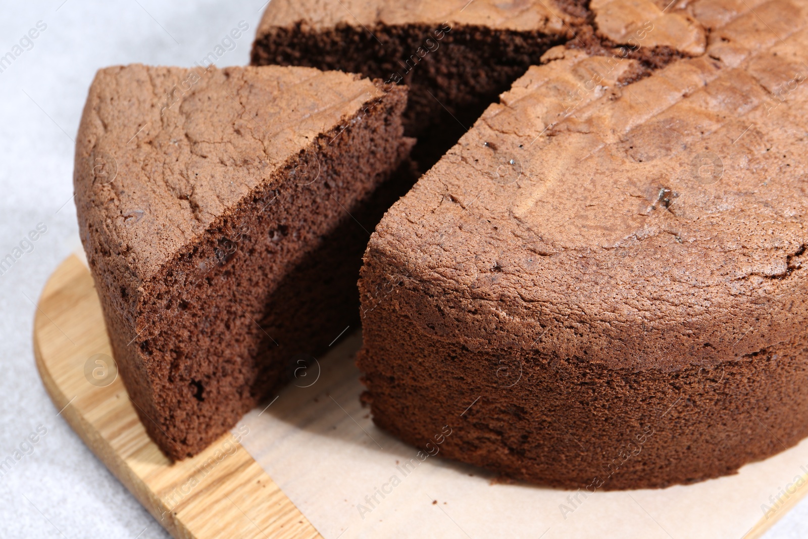 Photo of Cut chocolate sponge cake on light table, closeup